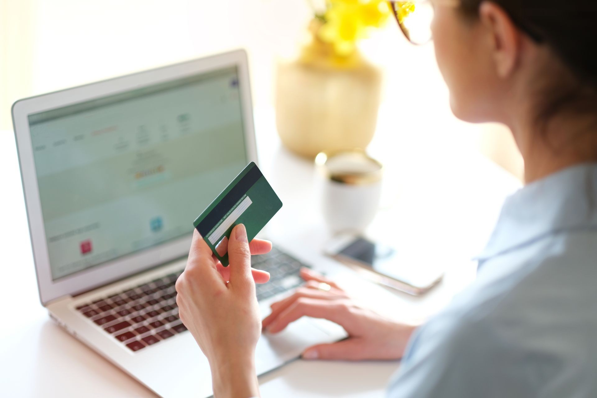 Woman holding in hand a credit card,while is doing shopping online.